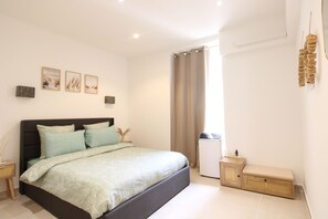 Ein Schlafzimmer mit einem Bett, einem Nachttisch, einem kleinen Schrank und einem Fenster mit Vorhängen.