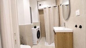 A modern bathroom with a toilet, washing machine, and sink. - Calm Elegant Apartment in the Heart of Nice (Nice)