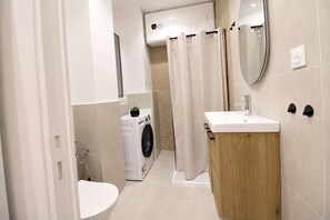 Ein modernes Badezimmer mit Toilette, Waschmaschine und Waschbecken.