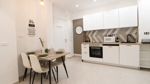 A modern kitchen with white cabinets, a microwave, and a stove. There is a dining table with chairs and a vase of flowers. - Calm Elegant Apartment in the Heart of Nice (Nice)