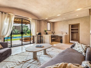 Amplia sala de estar con vista a la piscina, una cocina y un espacio de descanso.