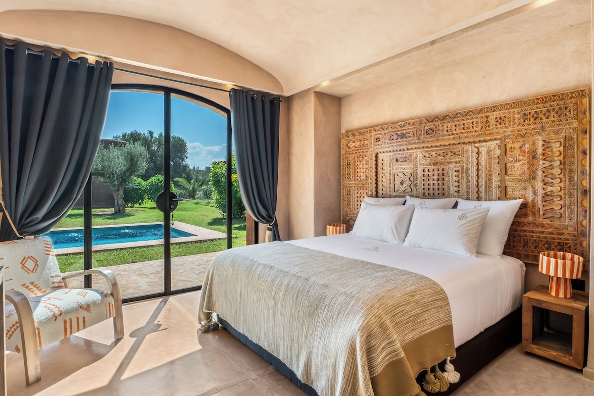 Un dormitorio con una cama grande, vistas a una piscina y un cabecero decorativo.