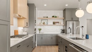 Eine moderne Küche mit grauen Schränken, einem Edelstahlkühlschrank und einem eingebauten Backofen.