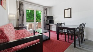 A room with a bed, a dining table with chairs, a TV, and a window with curtains. - Bright apartment for 4 people, with a balcony (Grasse)