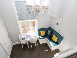 A corner seating area with a window, a chandelier, and a small table with a chair.