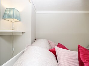 Ein Schlafzimmer mit Bett, Kissen, einer Lampe und einer Steckdose.