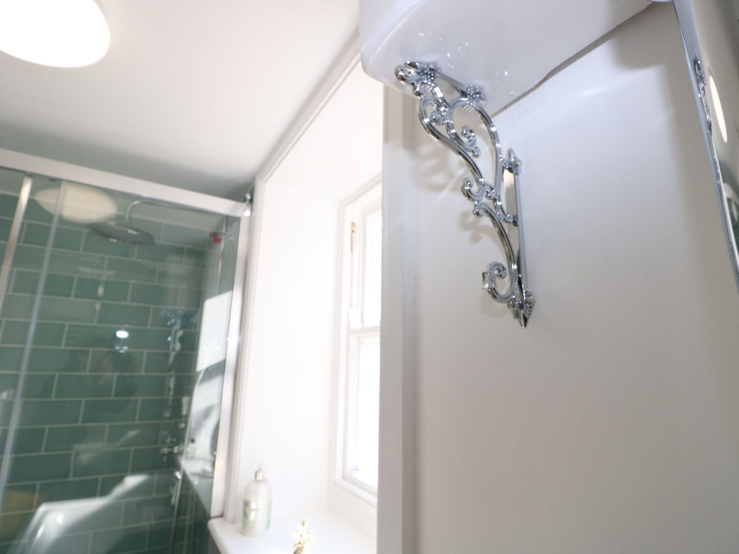 A bathroom with a shower, a glass door, and a white wall.