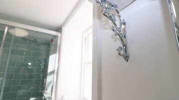 A bathroom with a shower, a glass door, and a white wall.