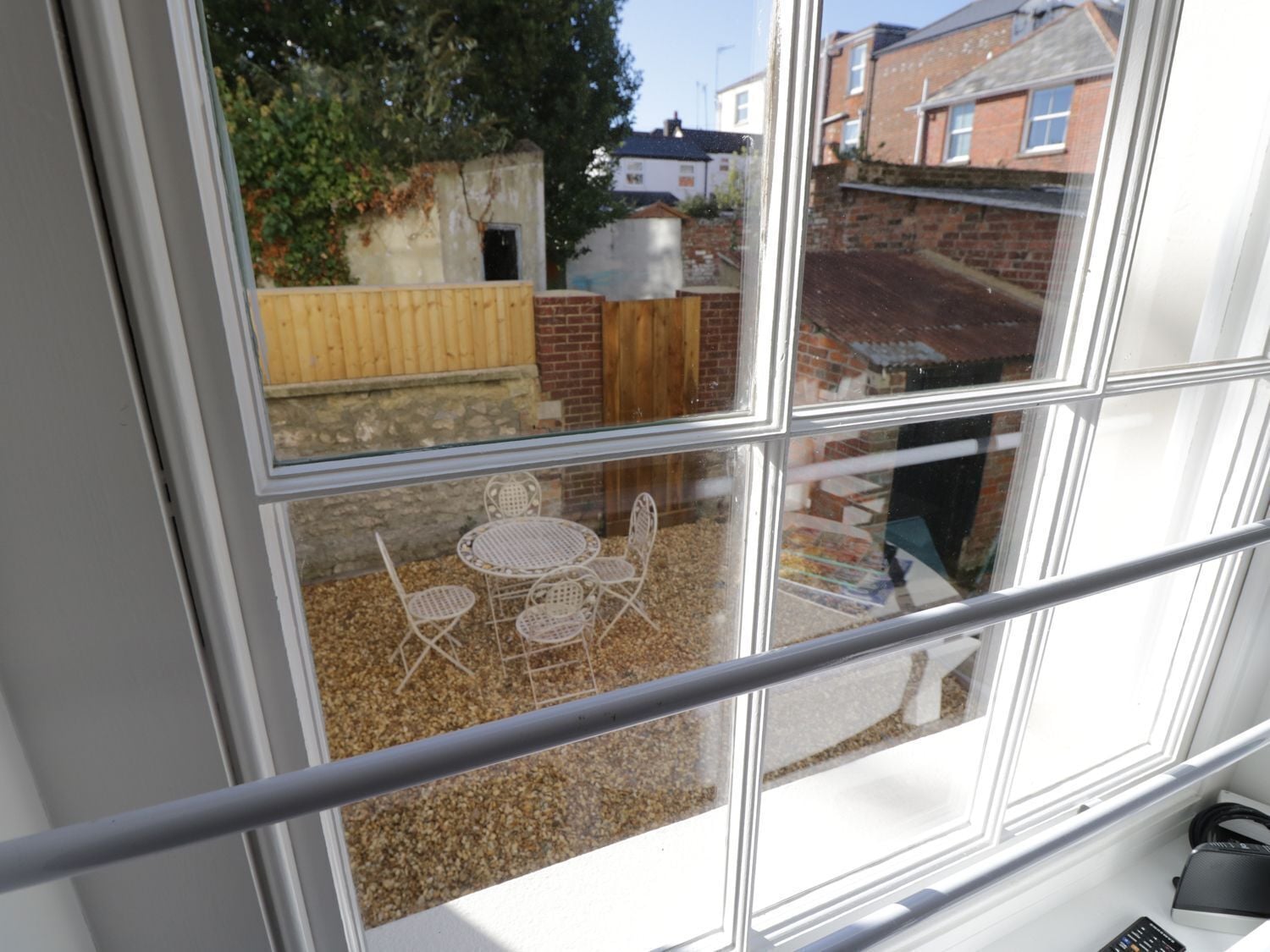 A window with a view of a patio area, including a table and chairs.