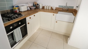 A kitchen with a gas stove, oven, white cabinets, a wooden countertop, and a sink. - Hamilton's Studio (Ryde)
