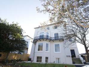 A multi-story white building with a balcony, a front door, and a staircase leading to the entrance. - Hamilton's Studio (Ryde)