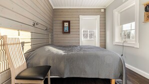 A bedroom with a bed, a chair, a window, and a door.