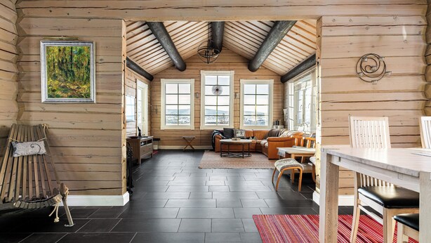 A log cabin interior with a dining area, a sofa, and a painting on the wall.