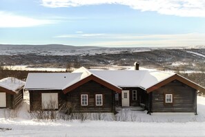 A wooden cabin with a snow-covered roof, a chimney, and a number '116' on the side.