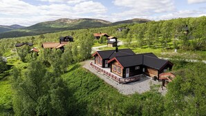 A remote cabin-style hotel with multiple buildings, surrounded by lush greenery and hills in the background.