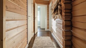 A wooden hallway with a rug, wooden walls, and a fur coat hanging on the wall.