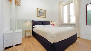 A bedroom with a bed, bedside tables, a radiator, and a window with curtains. - Piazza Vittorio - Recently redecorated apartment for 4 (Roma)