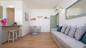 A modern living room with a sofa, a dining table with chairs, a kitchen area with stools, and a large mirror. - Piazza Vittorio - Recently redecorated apartment for 4 (Roma)