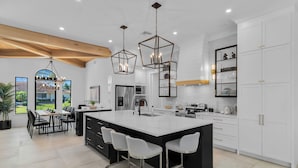 Cozinha moderna com uma ilha grande, banquetas e luminárias pendentes.