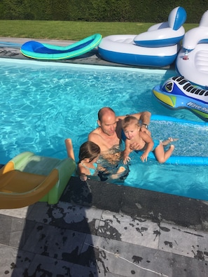 A swimming pool with inflatable toys and a slide.