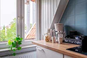 Eine Küchenarbeitsplatte mit einer Kaffeemaschine, einem Keksdose und einem Schild mit der Aufschrift 'But First Coffee'.