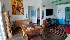 Ein Wohnzimmer mit einem Holztisch, einer Couch, einem Fernseher und einer farbenfrohen Tür.