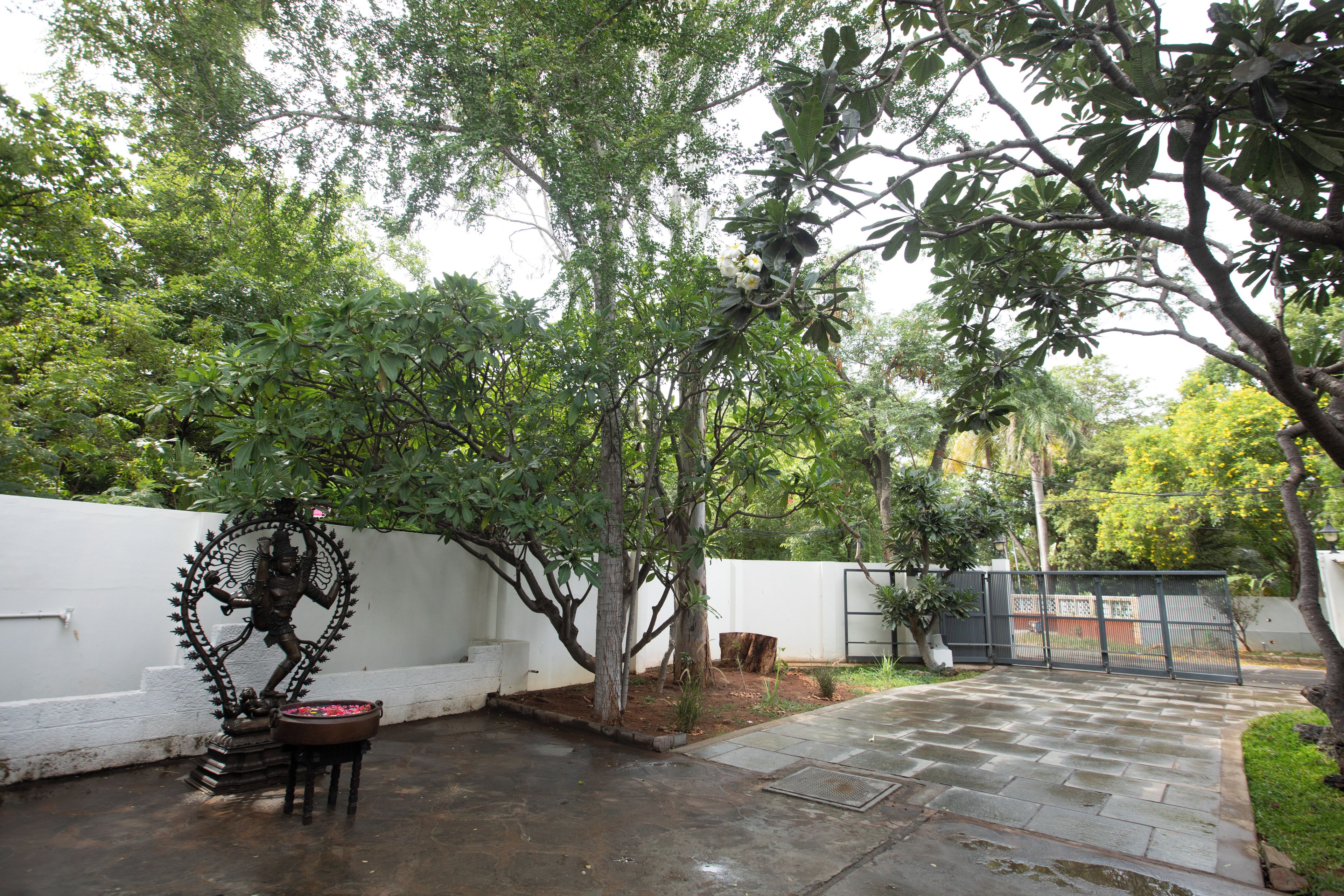 A courtyard with a statue, a white wall, and a paved walkway.
