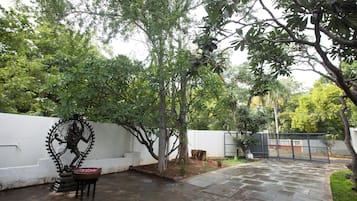 A courtyard with a statue, a white wall, and a paved walkway.