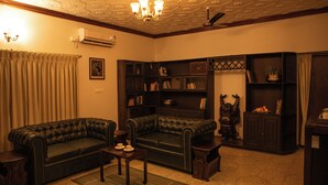 A living room with two dark leather sofas, a small table, a bookshelf, and a decorative statue.