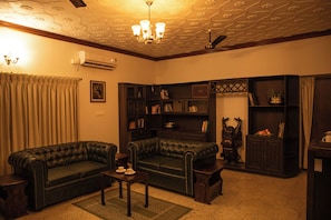 Una sala de estar con dos sofás de cuero oscuro, una mesita, una estantería y una estatua decorativa.