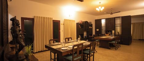 A dining area with a table set for four, chairs, a ceiling fan, and a chandelier.
