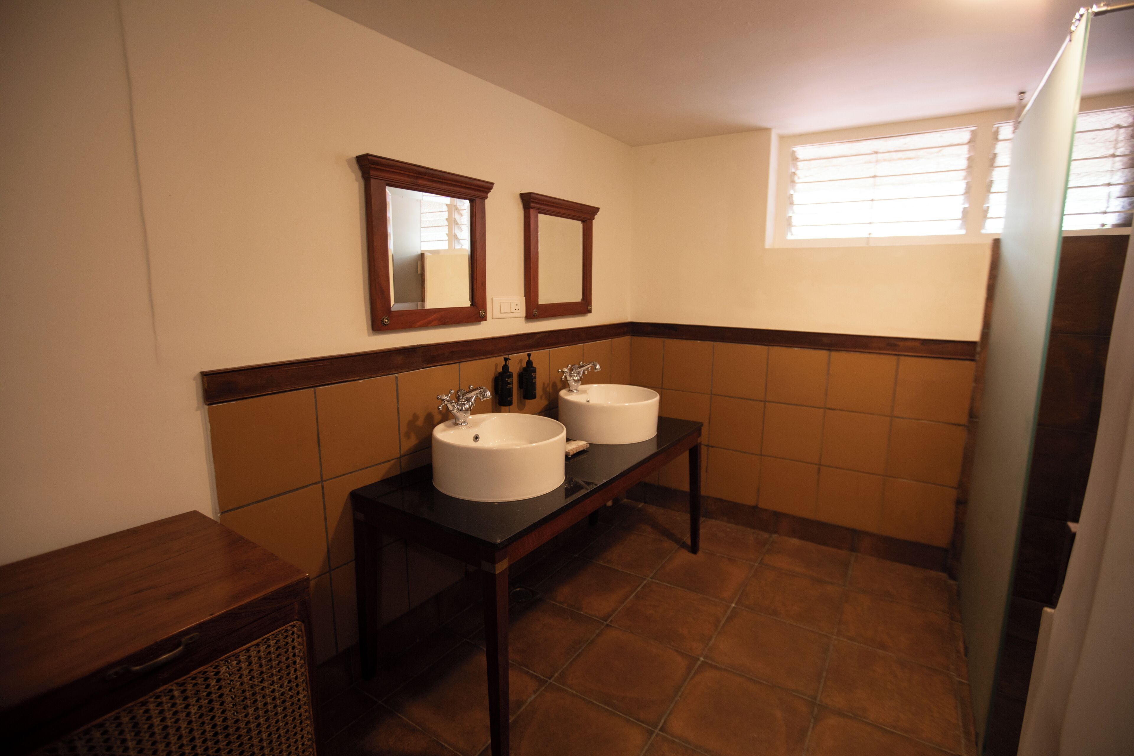 A bathroom with two sinks, a mirror above each sink, and a window with blinds.
