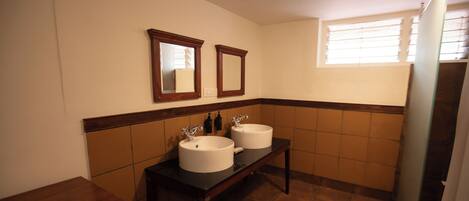 A bathroom with two sinks, a mirror above each sink, and a window with blinds.