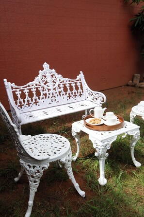 A white outdoor seating area with a bench and two chairs, a small table with a tray, and a pitcher. - Akshaya Bungalow Coimbatore (Coimbatore)
