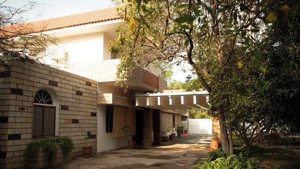 A building with a brick facade, a covered walkway, and potted plants.