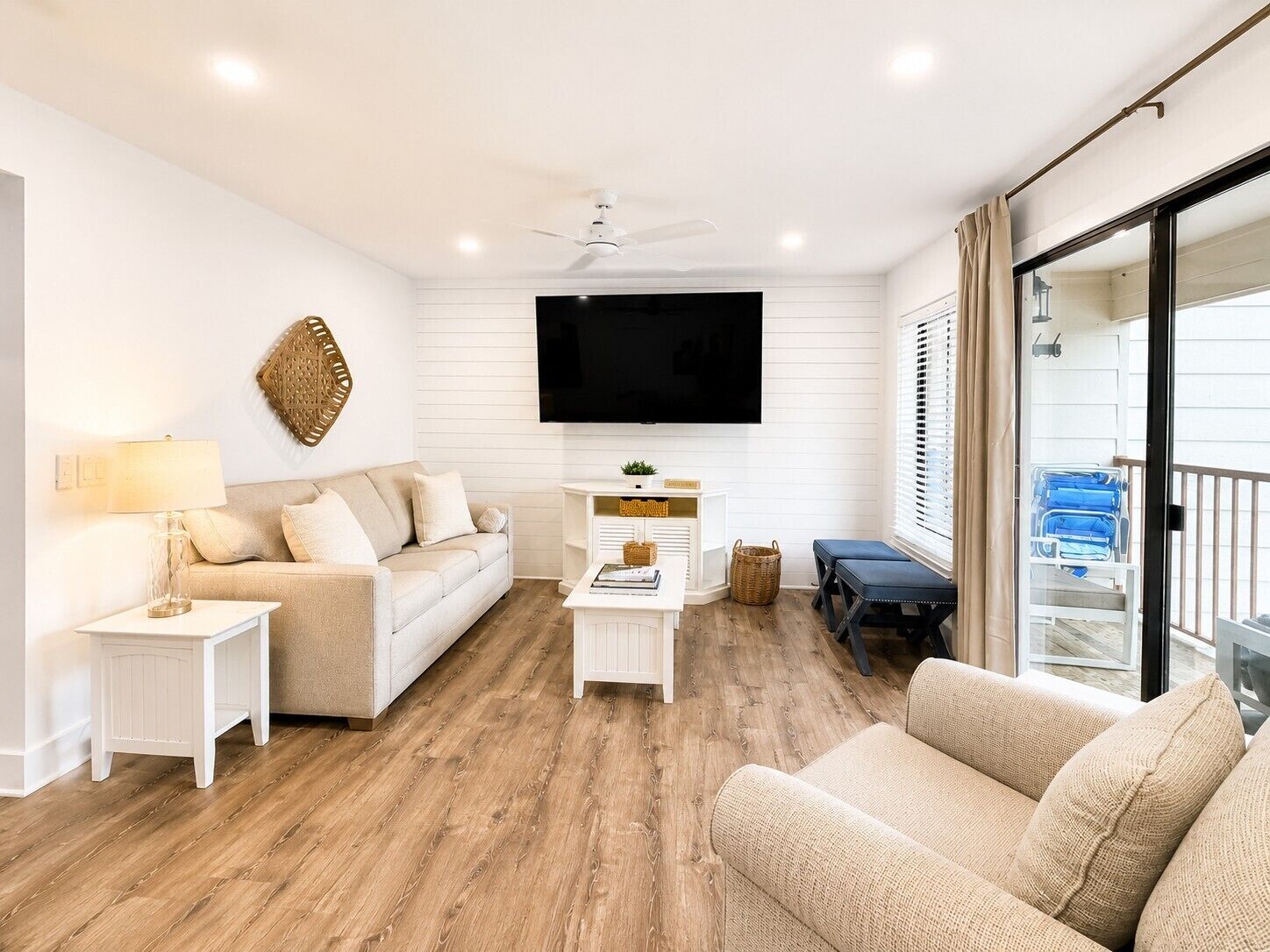 Un salon moderne avec un canapé, une table basse, un téléviseur et un balcon où sont entreposées des valises.