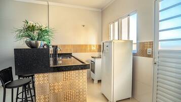 A kitchen with a black countertop, a white refrigerator, and a patterned backsplash.