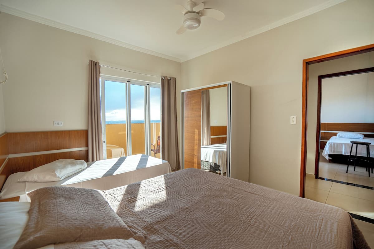 Habitación de hotel con dos camas, un balcón, un espejo grande y vistas al cielo.