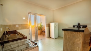 A kitchen with a gas stove, a refrigerator, a sink, and a small island with a black countertop.