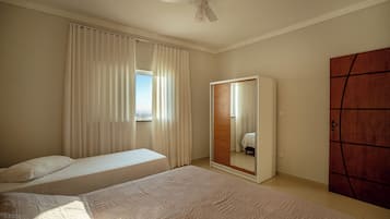 Una camera da letto con due letti, una ventola a soffitto, un armadio e uno specchio.