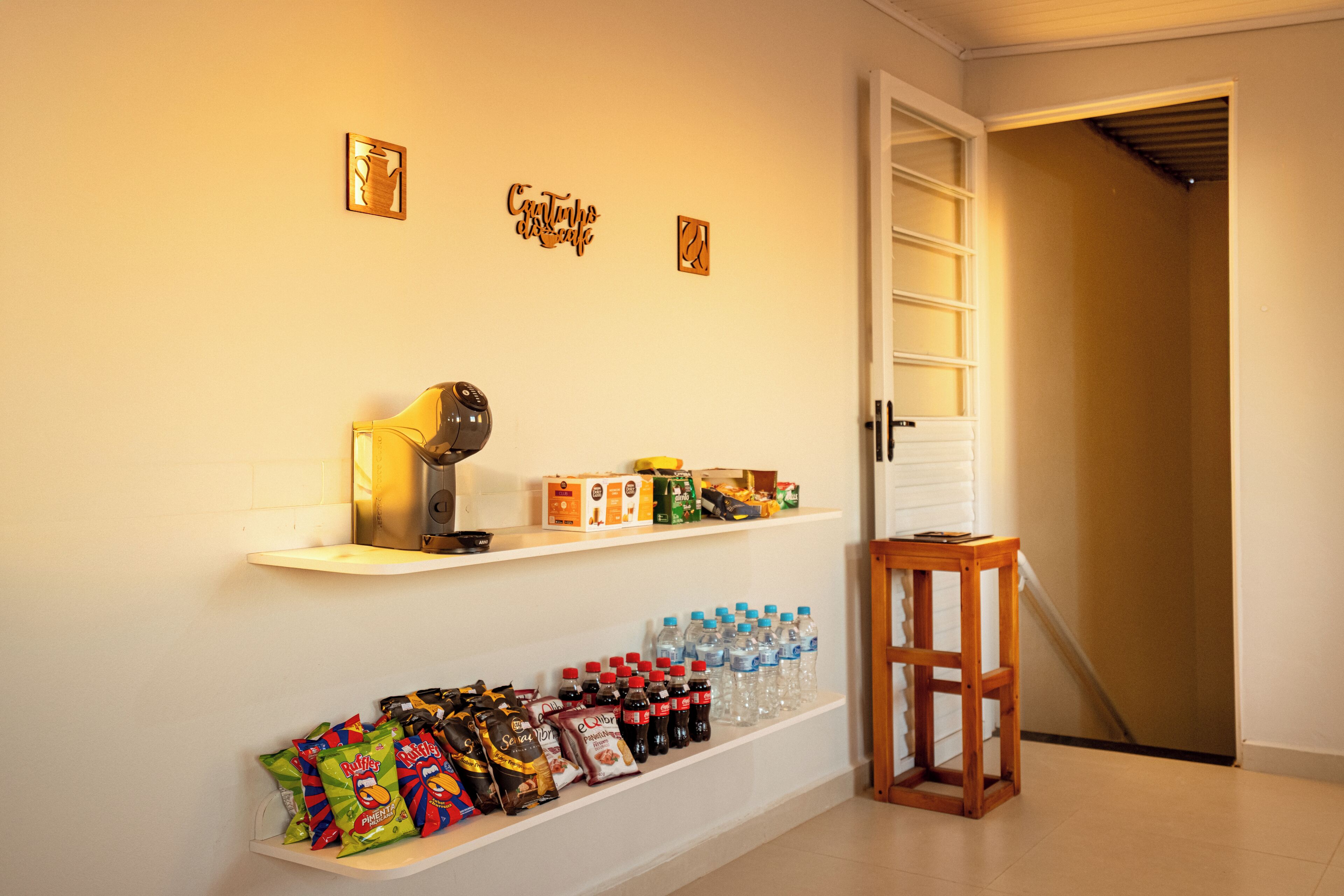 A hallway with a shelf displaying snacks, bottled water, and a coffee machine.