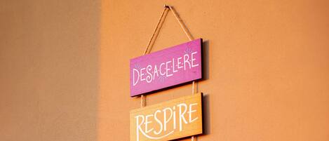 A wall with four wooden signs hanging vertically, each with a different word written on it.