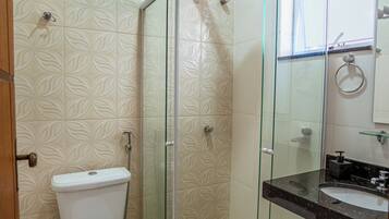 A bathroom with a toilet, a glass shower enclosure, and a sink with a mirror.
