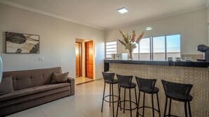 A modern kitchen with a bar area, a sofa, and a dining area with chairs.