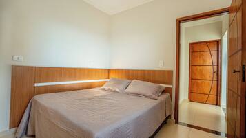 A bedroom with a bed, wooden headboard, and a door leading to another room.