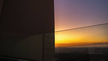 A view from a window with a building's edge and a sunset.