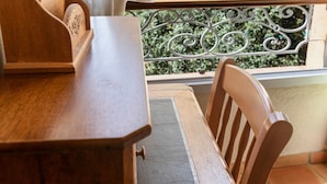 A wooden table with a chair, a window with a metal railing, and a view of greenery outside. - Guest Room 'La Fenière' with Shared Pool, Garden & Summer Kitchen, Wi-Fi (Carcès)