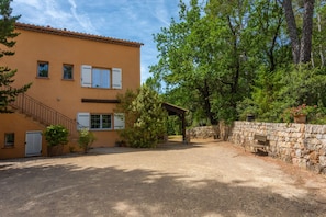 A two-story building with a gravel driveway, a stone wall, and a wooden bench. - Bed and Breakfast 'La Fenière' with Shared Pool, Shared Terrace and Wi-Fi (Carcès)