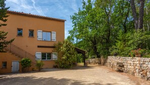 A two-story building with a gravel driveway, a stone wall, and a wooden bench. - Le Temps des Cerises Guest Room with Shared Pool, Garden, Summer Kitchen, and Wi-Fi (Carcès)