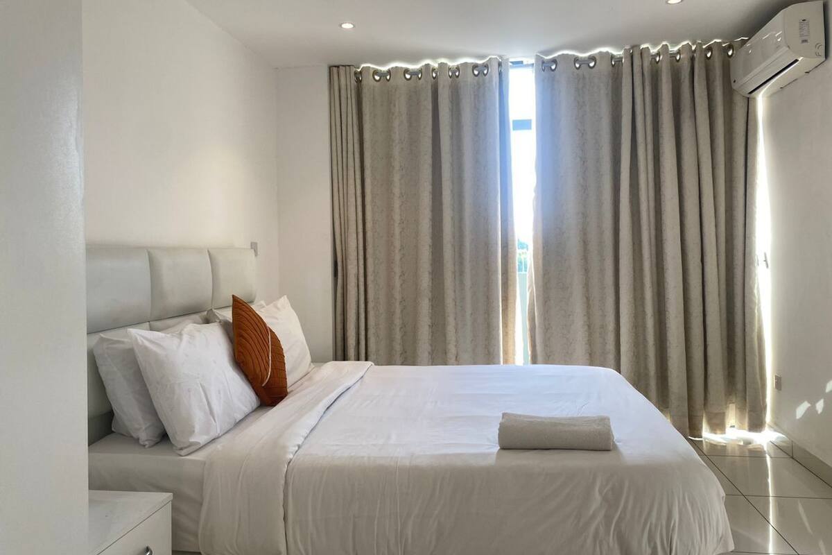 A bedroom with a bed, curtains, and an air conditioning unit.